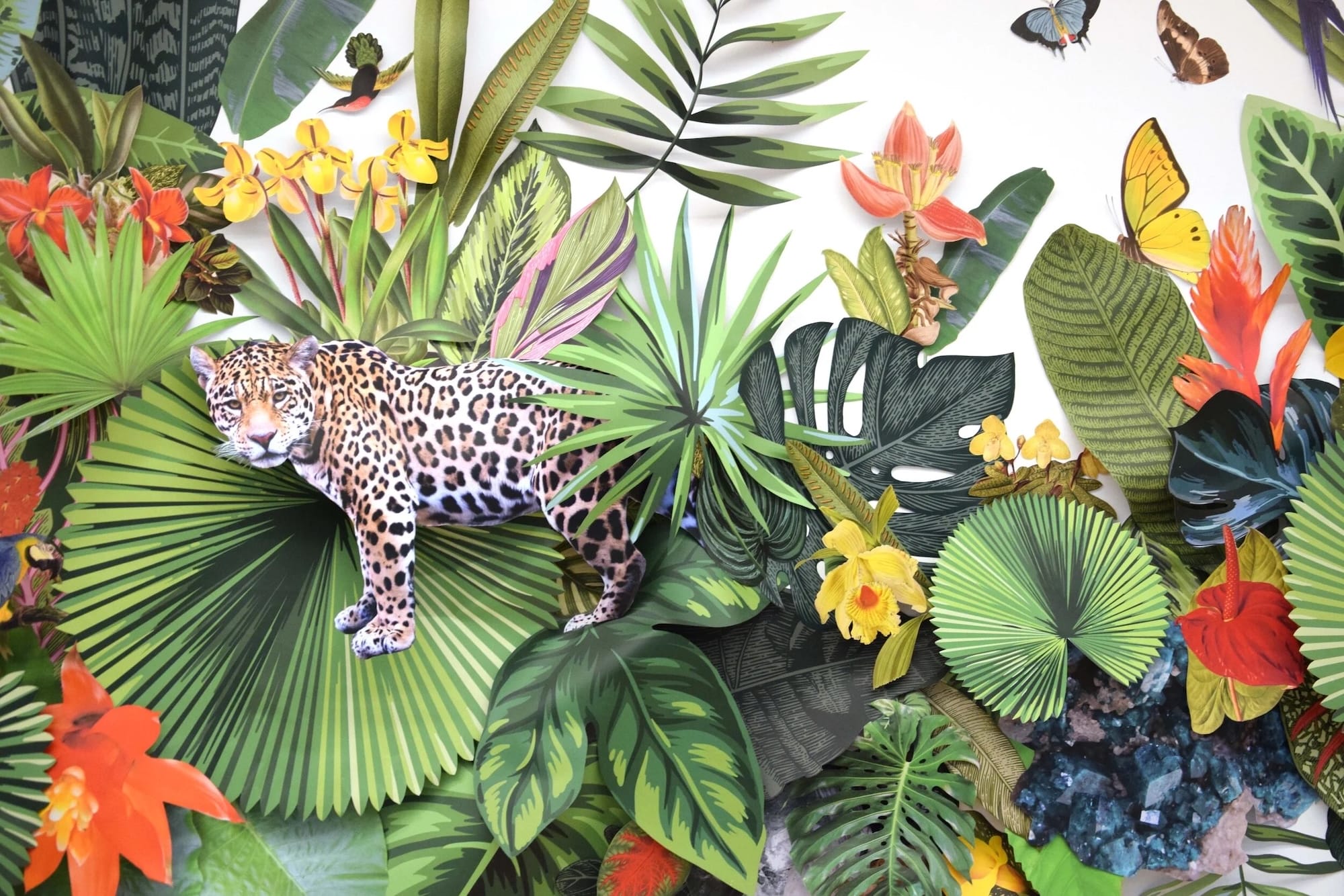 A detail of a paper installation by Clare Celeste of jungle foliage and animals on a wall