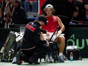 A tennis player gets his ankle taped by medical staff
