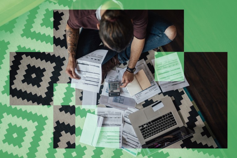 Top-down view of a person sorting through bills while sitting on a black and white rug on the floor