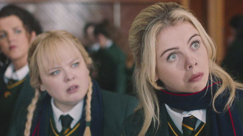 Saoirse-Monica Jackson as Erin standing in front of Nicola Coughlan as Clare and Jamie-Lee O'Donnell as Michelle in Derry Girls