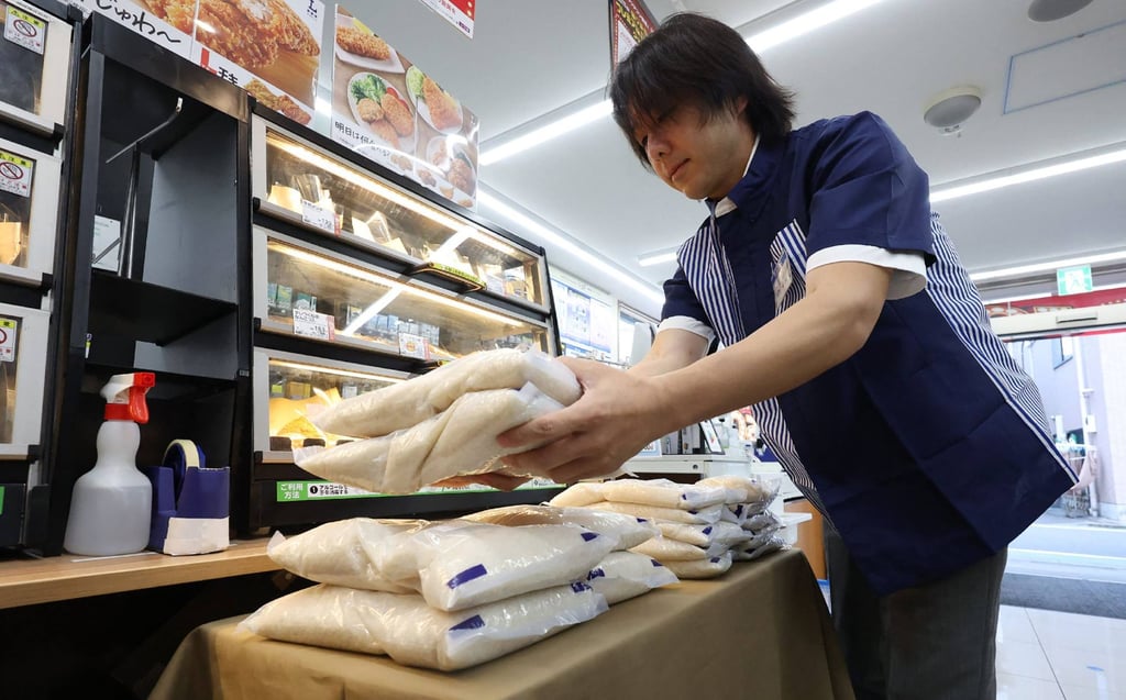 A staffmember displays bags of rice at a Lawson convenience store in Tokyo last year. Rice prices in Japan have soared by around two-thirds. Photo: AFP