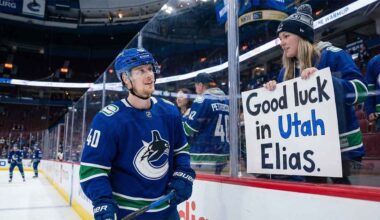 Vancouver Canucks center Elias Pettersson smiles as he looks up at a female fan pressing a handmade sign against the rink glass that reads "Good luck in Utah Elias." during pre-game warmups.