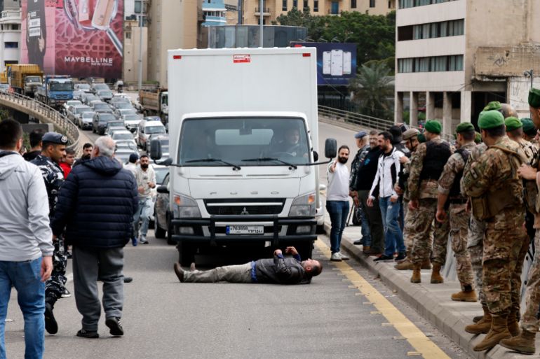 epa12749352 A taxi driver lies on the ground in front of a truck as taxi drivers block a main road with their vehicles during a protest in Beirut, Lebanon, on 17 February 2026. Taxi drivers blocked the Ring Highway with their vehicles to protest against the increased taxes and gasoline prices approved by the Cabinet during its meeting on 16 February. EPA/WAEL HAMZEH