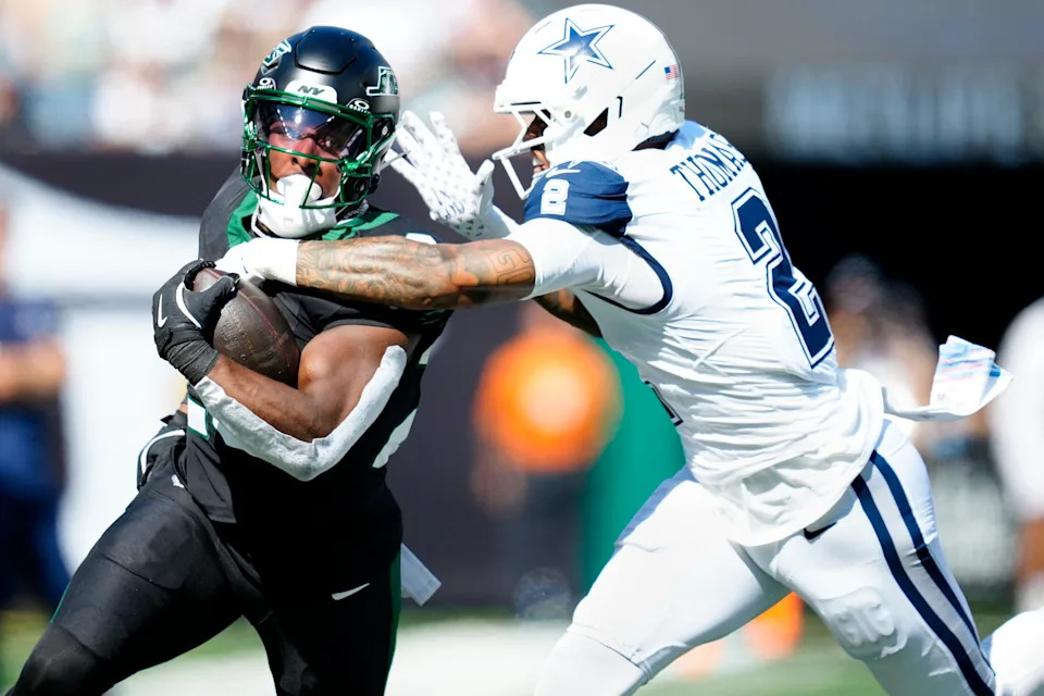 New York Jets running back Breece Hall (20) runs for a first down as Dallas Cowboys safety Juanyeh Thomas (2) attempts to tackle him in the first quarter, Sunday, October 5, 2025.