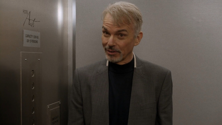 Lorne Malvo (Billy Bob Thornton) stands attentively by an open door in Fargo