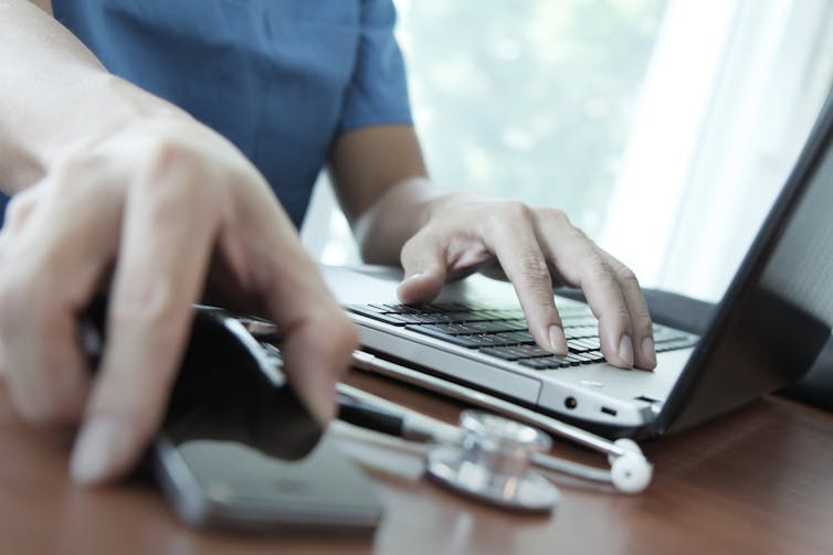 Doctor working with laptop computer in medical setting.