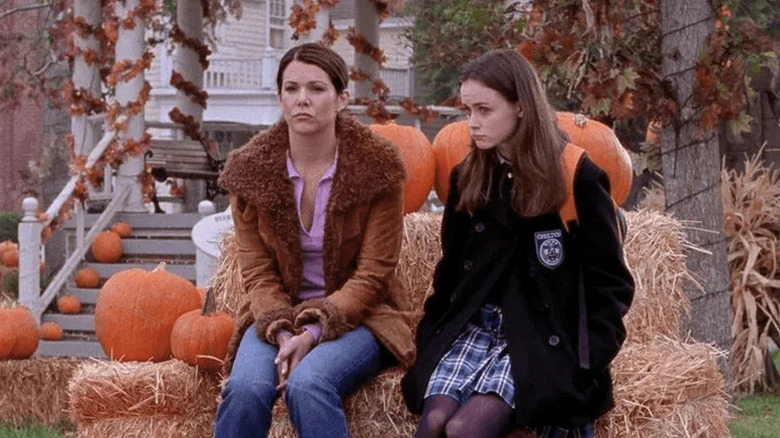 Lauren Graham as Lorelai and Alexis Bledel as Rory sitting in front of pumpkins looking forlorn in Gilmore Girls