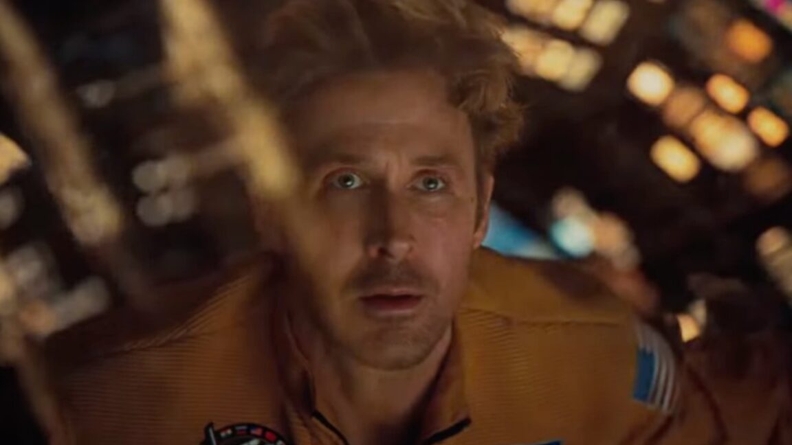 closeup of blond man in a spacesuit peering out through a window of his spacecraft in wonder