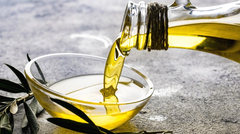 Olive oil being poured into a glass bowl.