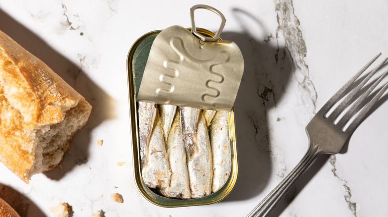can of sardines with a fork and some bread
