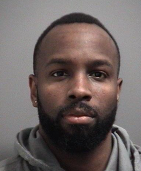 Police released headshot of a person looking directly at the camera.with short hair and a beard, wearing a hoodie, against a plain grey background.