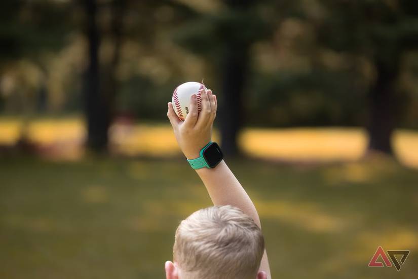 Child holding up a baseball with teal coloured smartwatch on his wrist