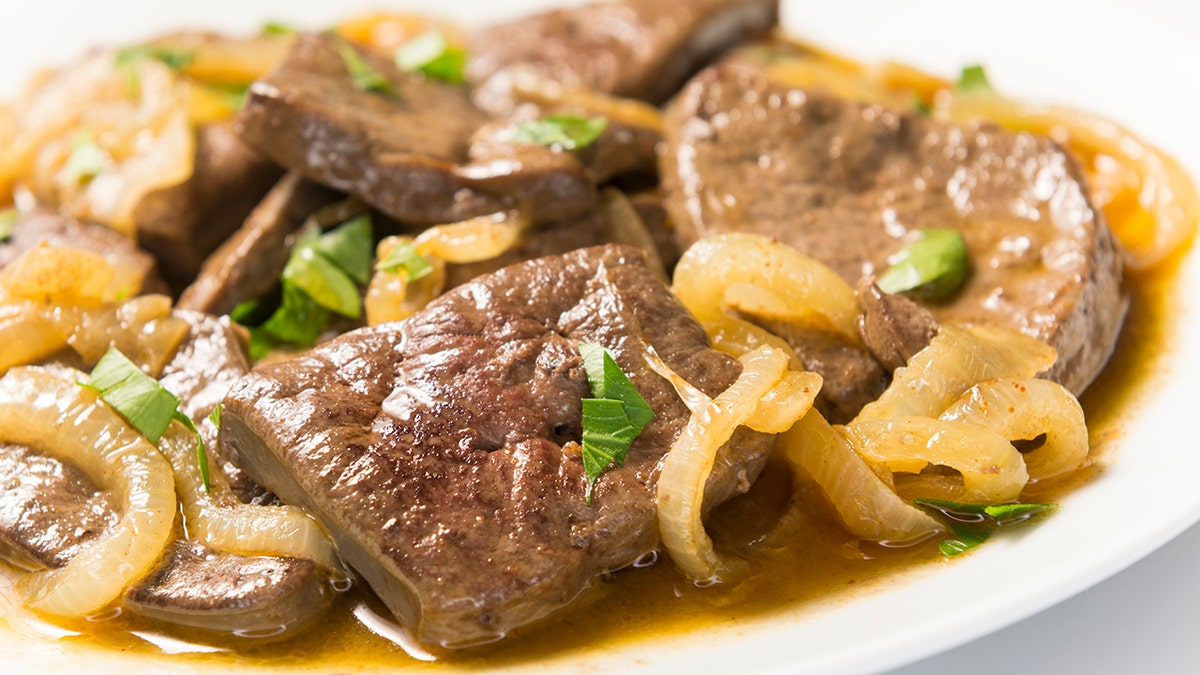 Veal liver-offal seen on plate with sauteed oniuons.