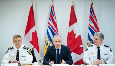 Prime Minister Mark Carney speaks during a round table with police, flanked by Surrey Police Chief Const. Norm Lipinski, left, and RCMP Deputy Commissioner Dwayne McDonald, right, at RCMP 'E' Division headquarters in Surrey, B.C., on Thursday.