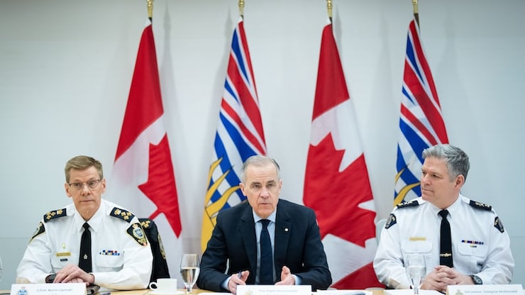 Prime Minister Mark Carney speaks during a round table with police, flanked by Surrey Police Chief Const. Norm Lipinski, left, and RCMP Deputy Commissioner Dwayne McDonald, right, at RCMP 'E' Division headquarters in Surrey, B.C., on Thursday.