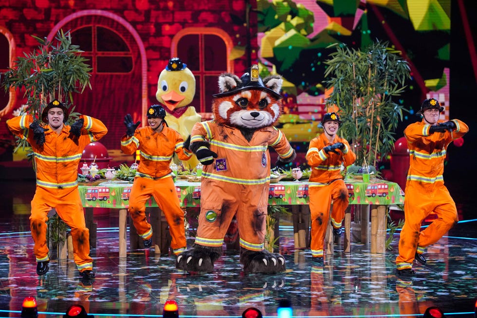 performance featuring characters in mascot costumes and dancers in orange outfits