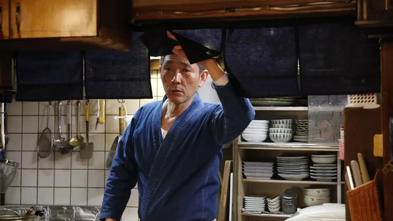 Kaoru Kobayashi as Master holding up flap to look out from kitchen in Midnight Diner