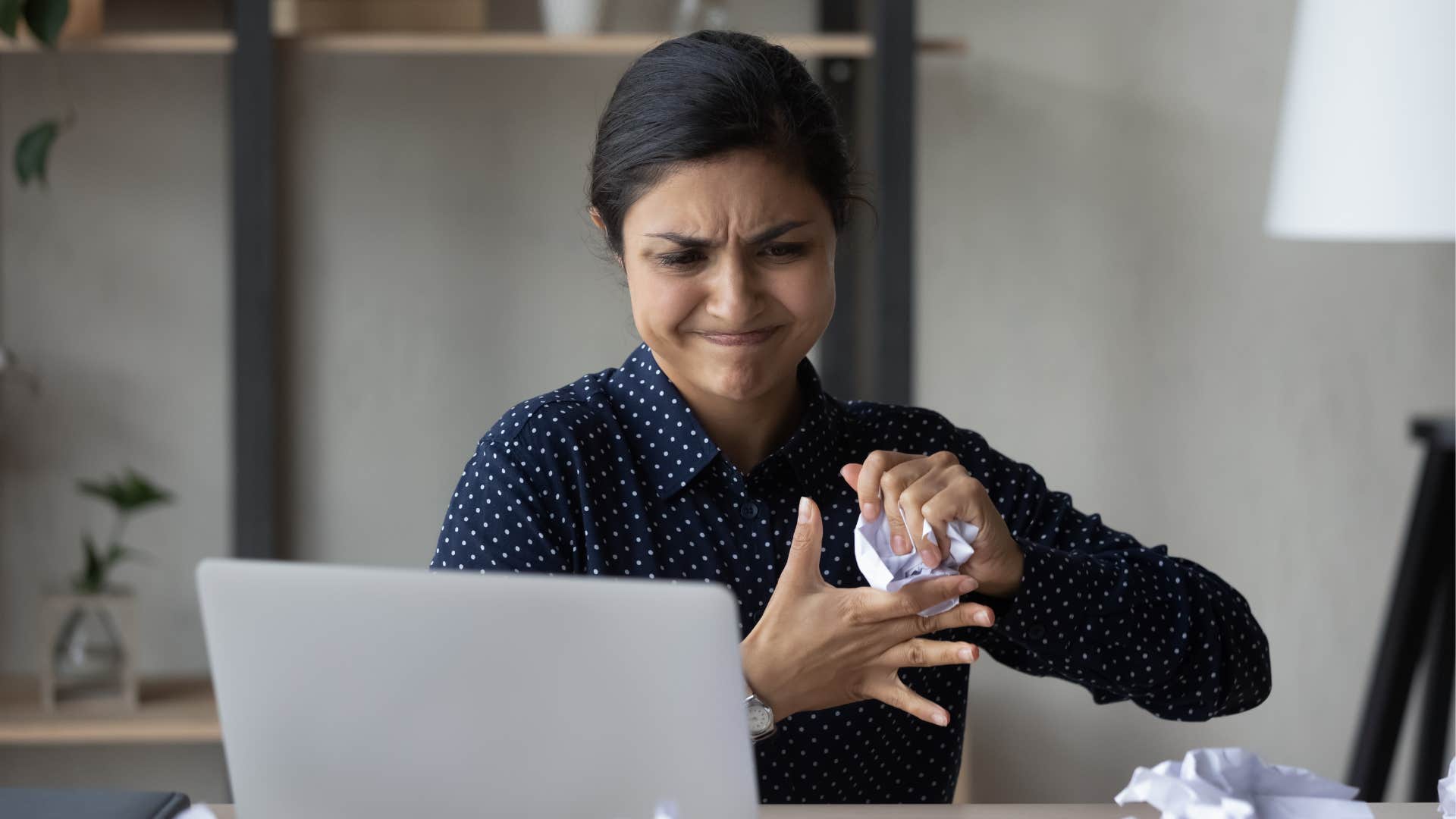Frustrated millennial wads paper showing not clocking out is stressful