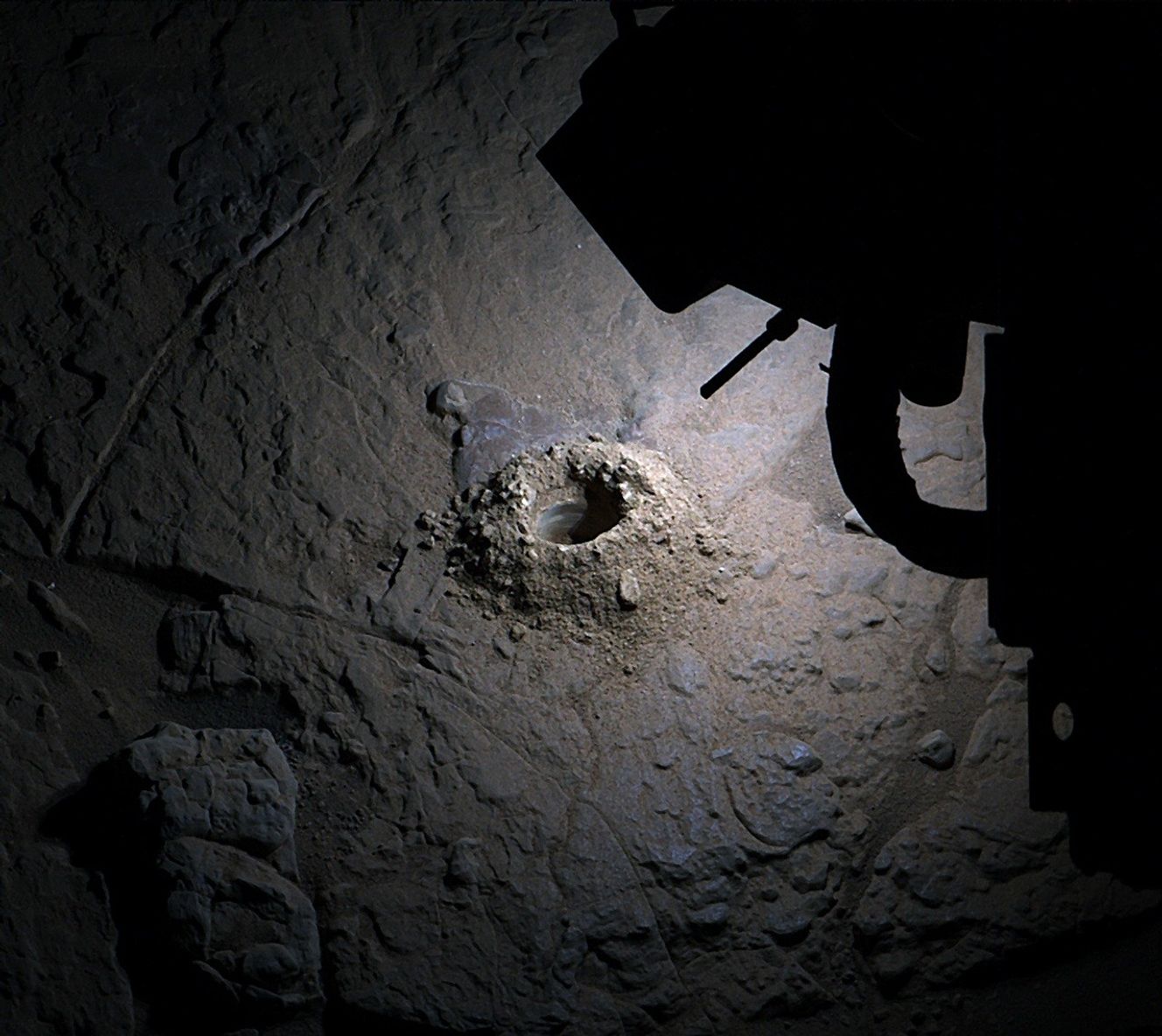 An image taken by NASA's Curiosity rover shows its LED lights lighting up a hole it drilled into the surface of the rock.