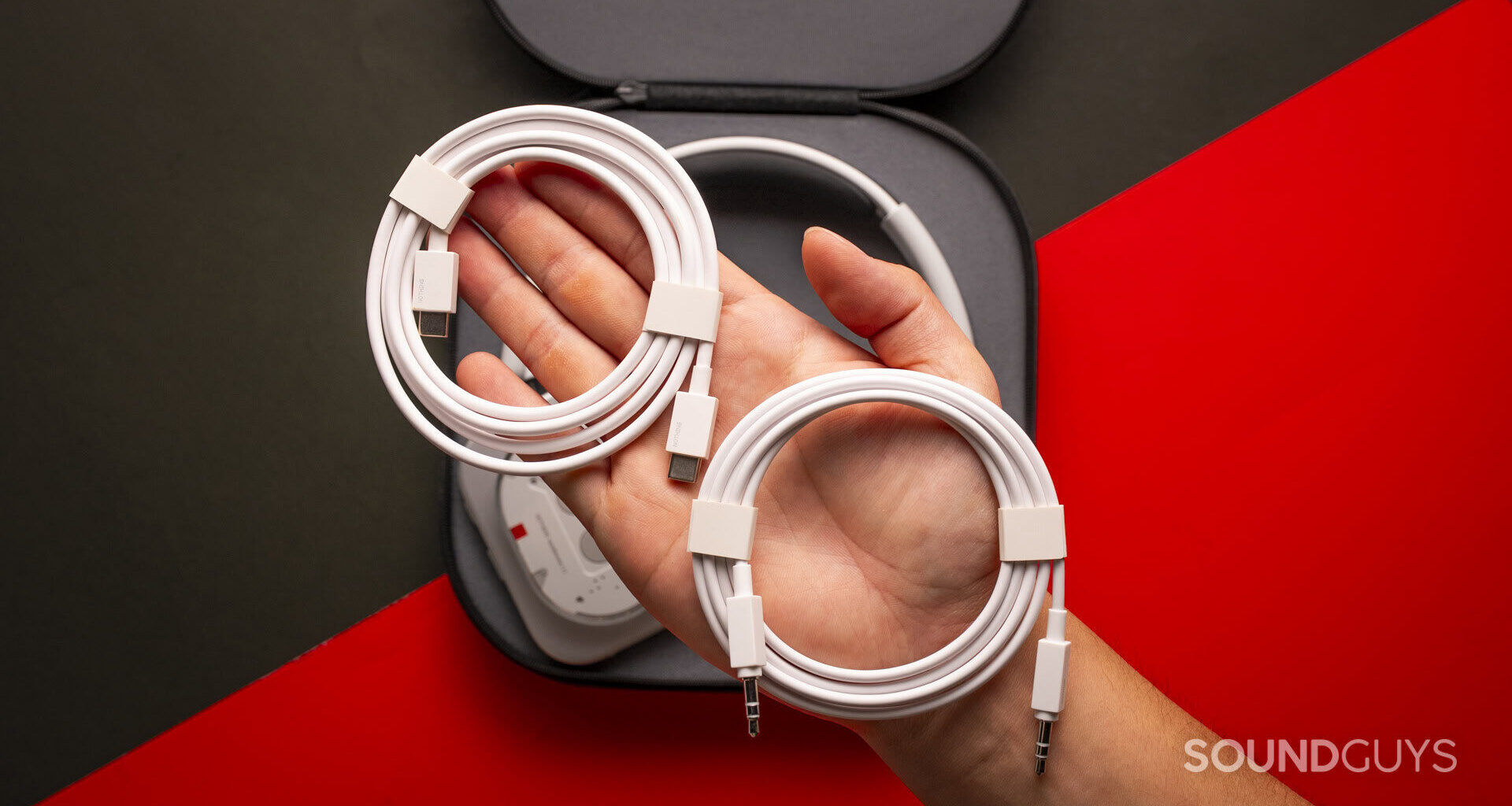 a hand holding white usb-c and 3.5mm cables