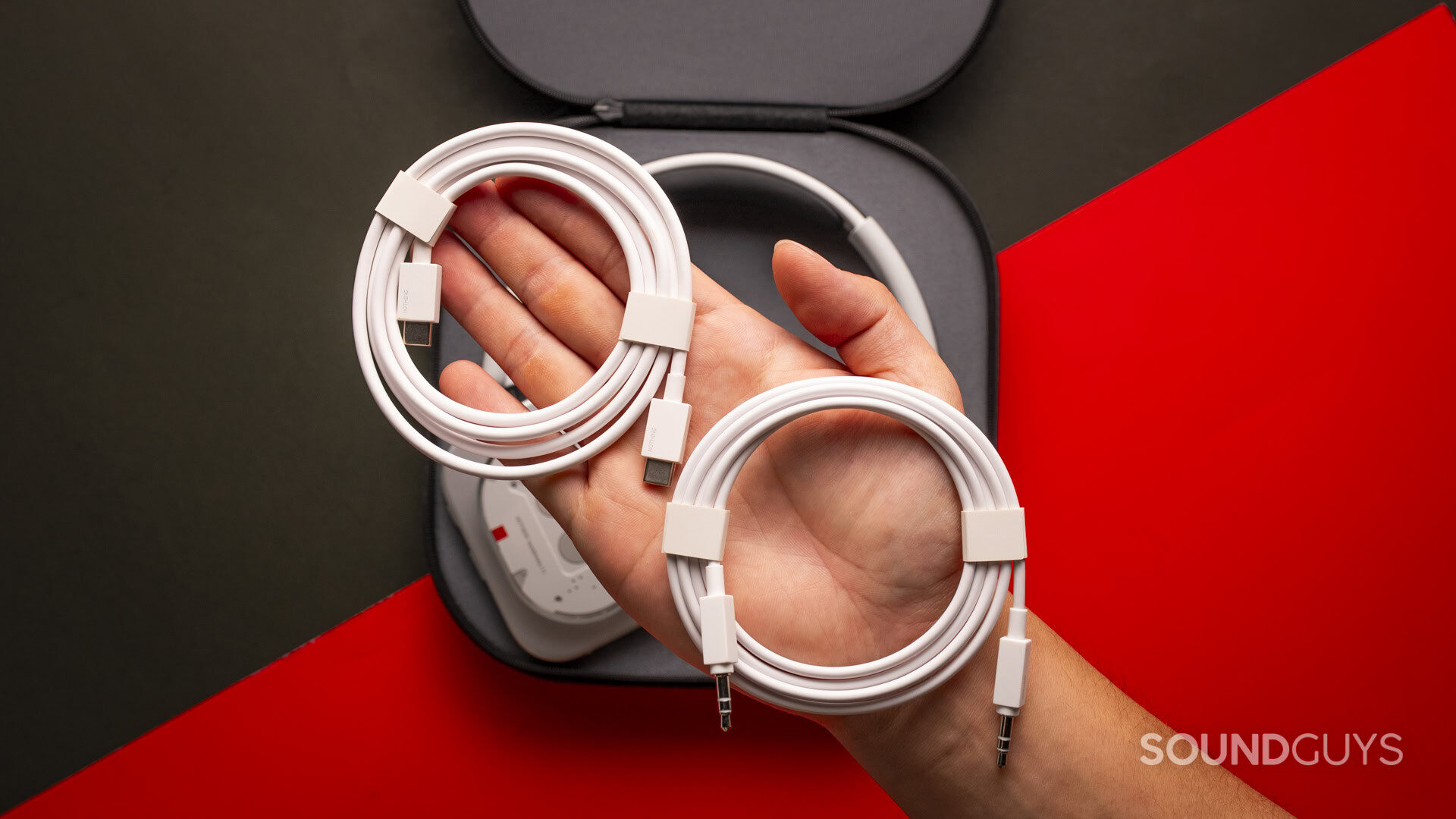 a hand holding white usb-c and 3.5mm cables