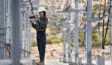 Woman in hard hat amid energy towers.