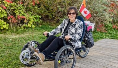 Lisa Carnevale on a specialized bike in front of bushes and with a Canadian flag.