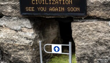 A miniature installation by Michael Pederson of a gap at the base of a stone wall with a gate and a replica digital sign that reads