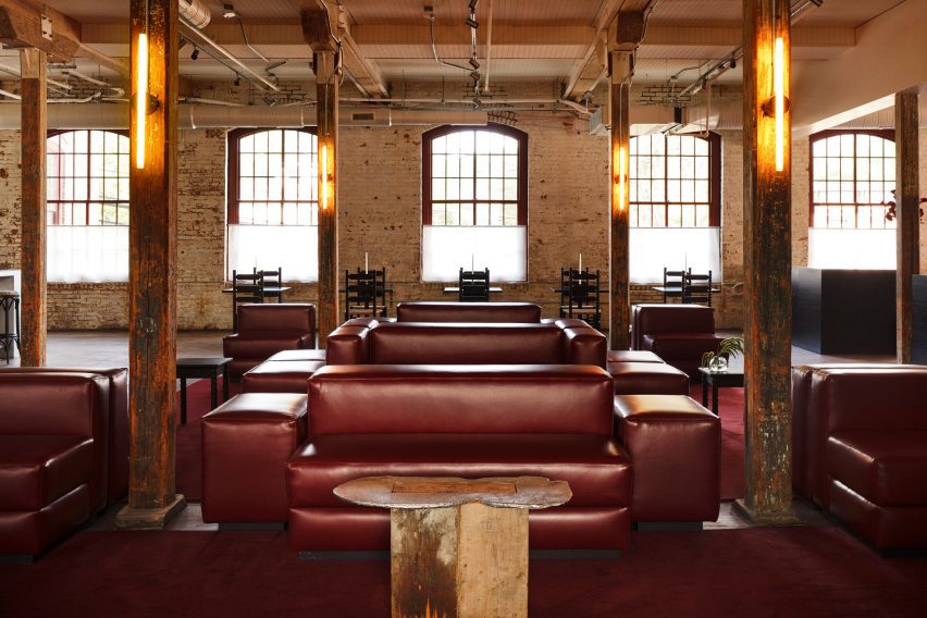 A bar lounge furnished with claret-hued modular sofas, which sit on a matching carpet