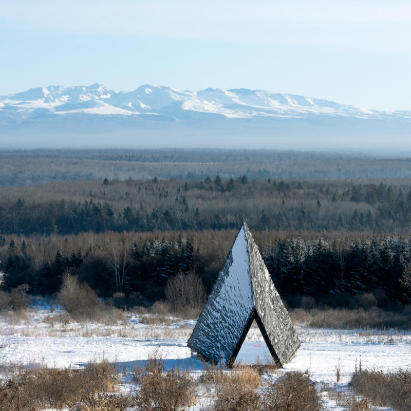 reflective red chamber emerges from prism mountain shelter’s charred wood shell