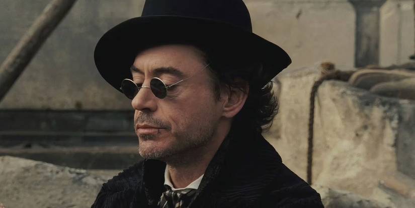 Robert Downey Junior as Sherlock Holmes wearing sunglasses and a black corduroy coat.