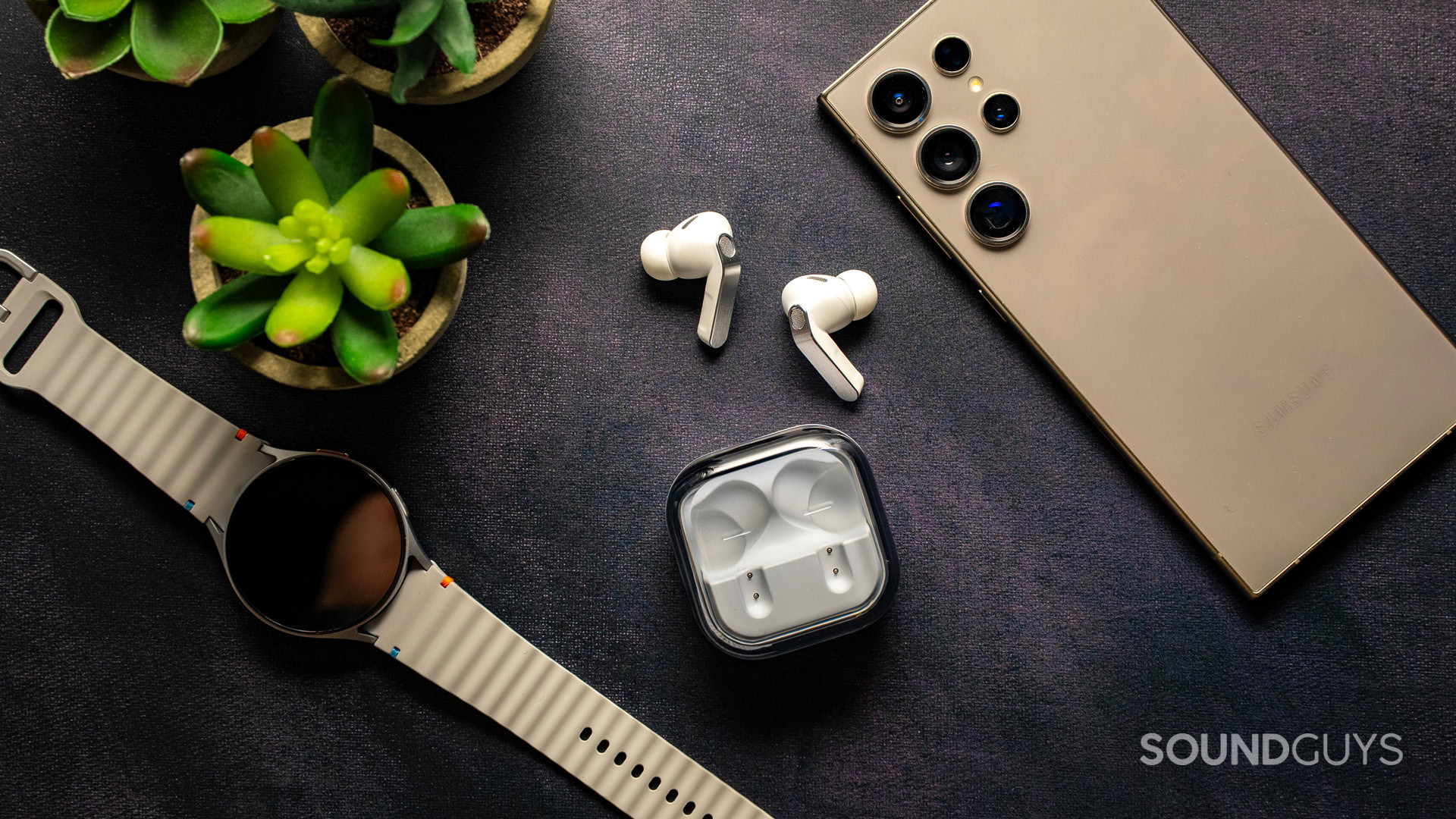 The Samsung Galaxy Buds 4 Pro sit among other Samsung gadgets.