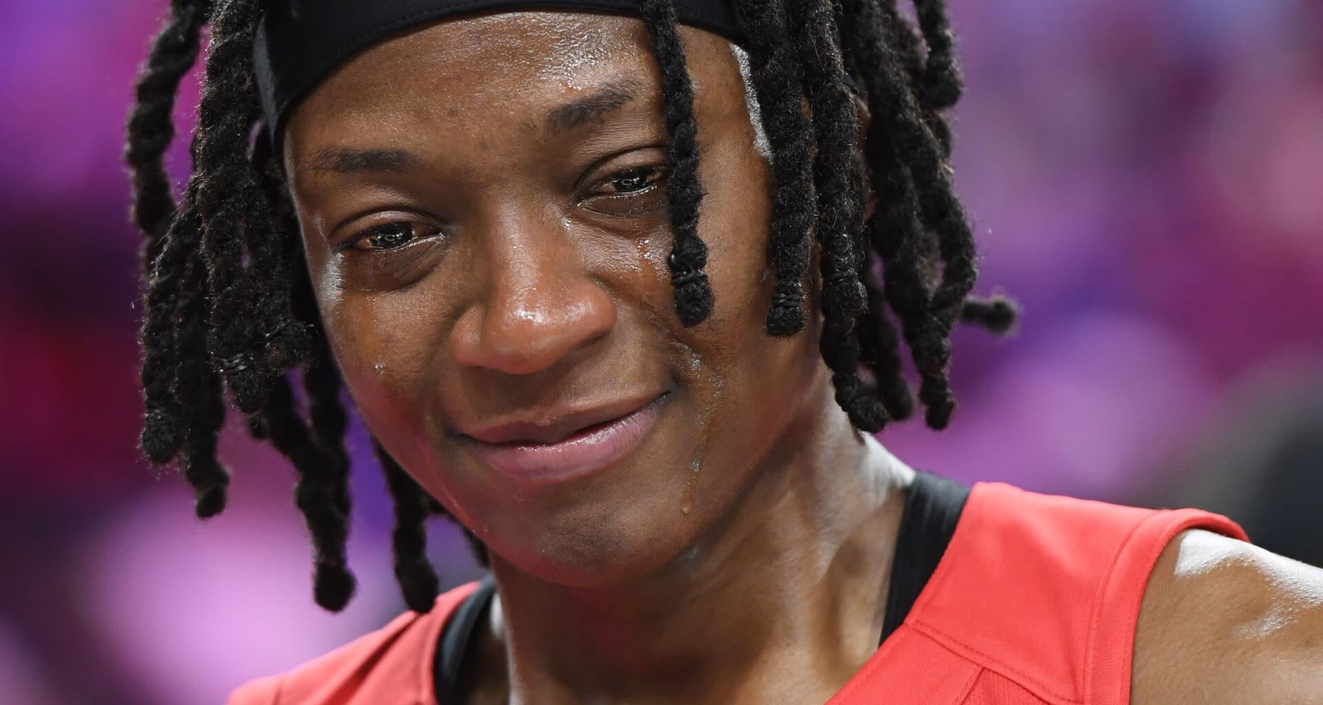 Erica Wheeler visibly emotional, wearing a red sports jersey, with a blurred background.