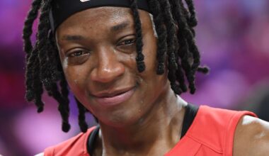 Erica Wheeler visibly emotional, wearing a red sports jersey, with a blurred background.