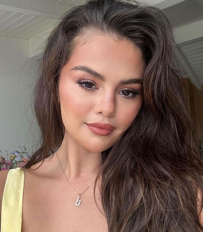 Selena Gomez with natural makeup and long hair in a casual indoor setting, related to Taylor Swift gift backlash. Selena Gomez with natural makeup and long hair in a casual indoor setting, related to Taylor Swift gift backlash.