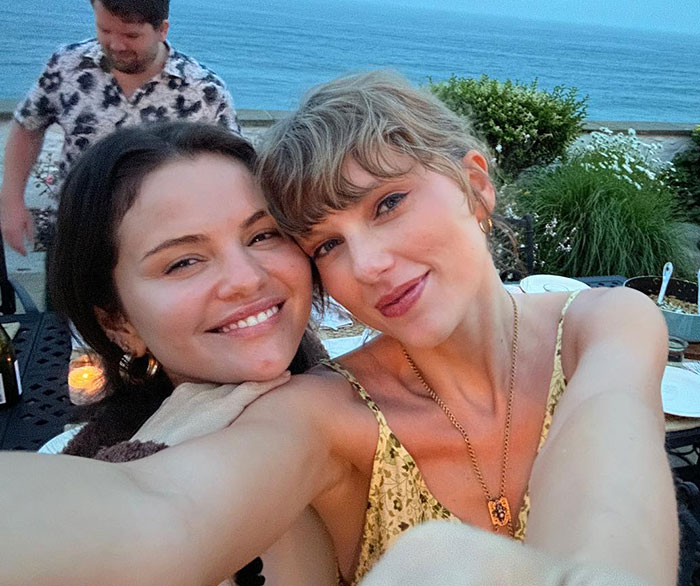 Taylor Swift and Selena Gomez smiling together outdoors near water, highlighting Taylor Swift's gift backlash. Taylor Swift and Selena Gomez smiling together outdoors near water, highlighting Taylor Swift's gift backlash.