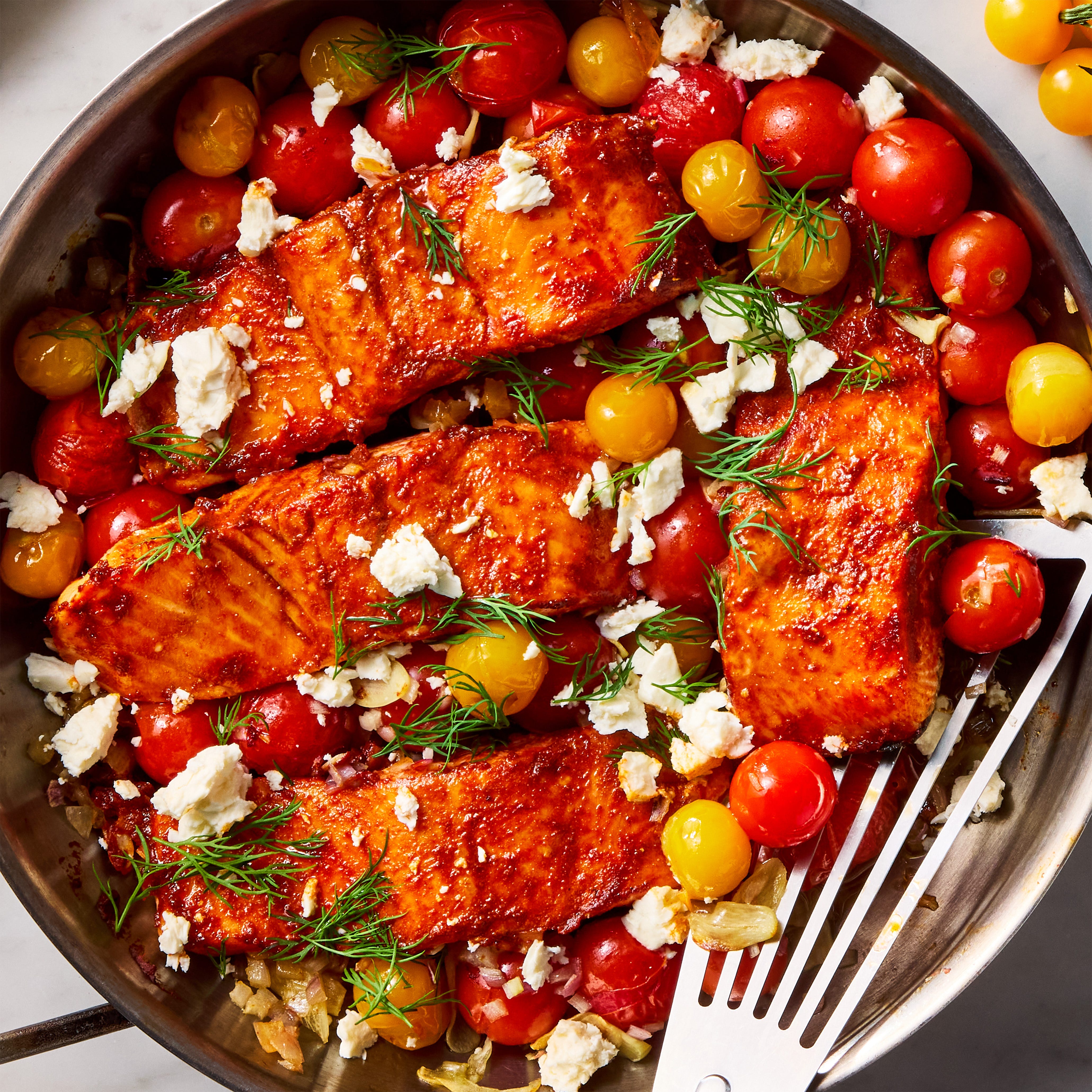 salmon filets are dusted with cumin and paprika, rubbed with spicy harissa paste, and roasted alongside cherry tomatoes, shallots, and garlic, then topped with fresh dill and creamy feta