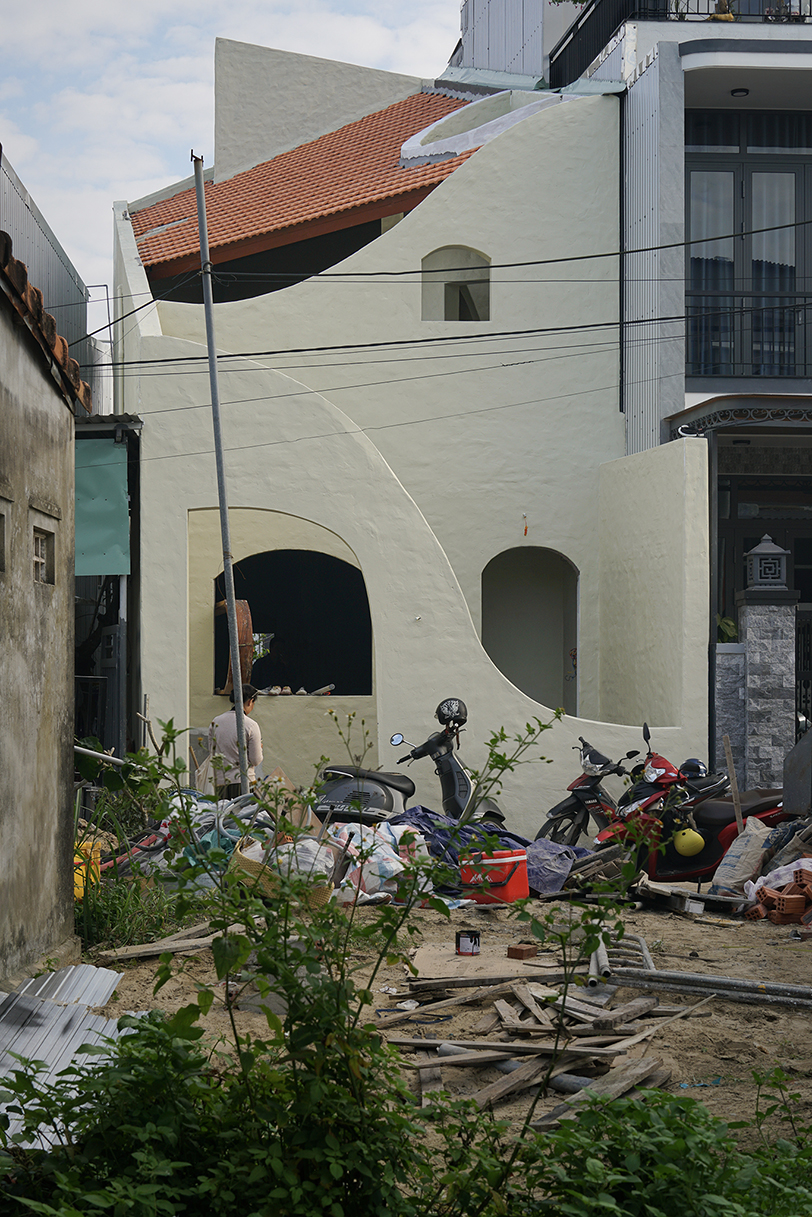 curved cutouts sculpt fluid voids within gabled residence in vietnam