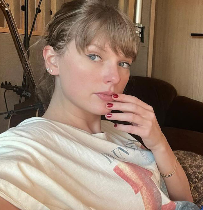 Taylor Swift posing indoors with hand near face, casual outfit, natural makeup sparking backlash over gift to Selena Gomez. Taylor Swift posing indoors with hand near face, casual outfit, natural makeup sparking backlash over gift to Selena Gomez.