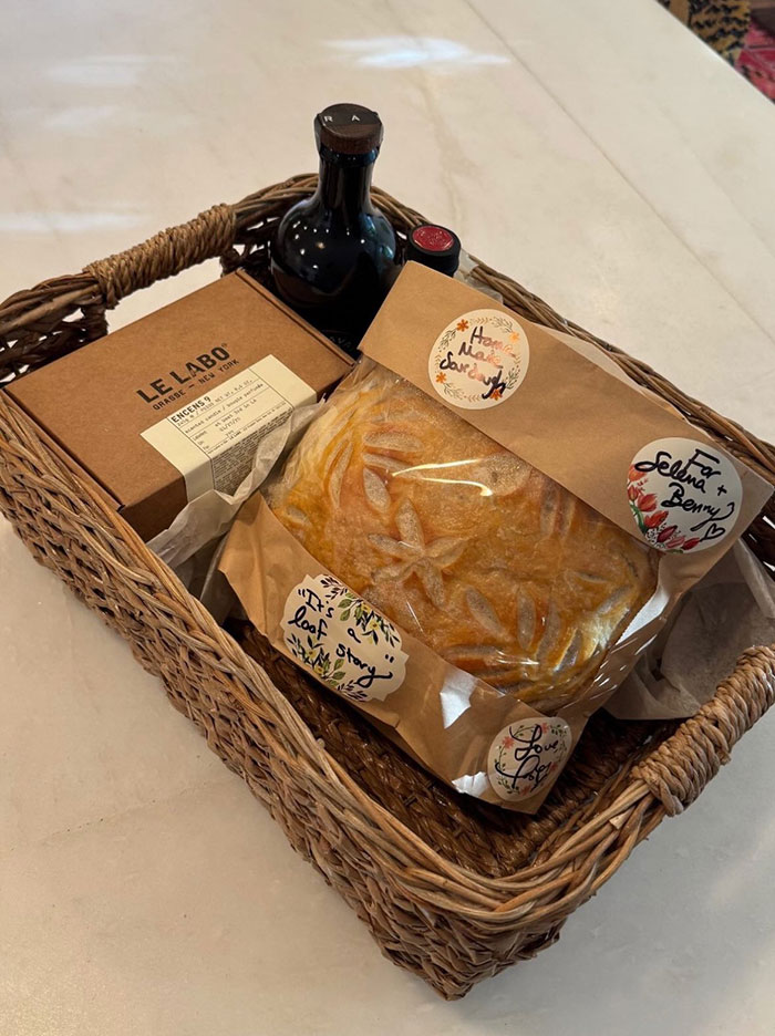 Wicker basket with a loaf of bread, a box of Le Labo incense, and two wine bottles as a Taylor Swift gift to Selena Gomez. Wicker basket with a loaf of bread, a box of Le Labo incense, and two wine bottles as a Taylor Swift gift to Selena Gomez.