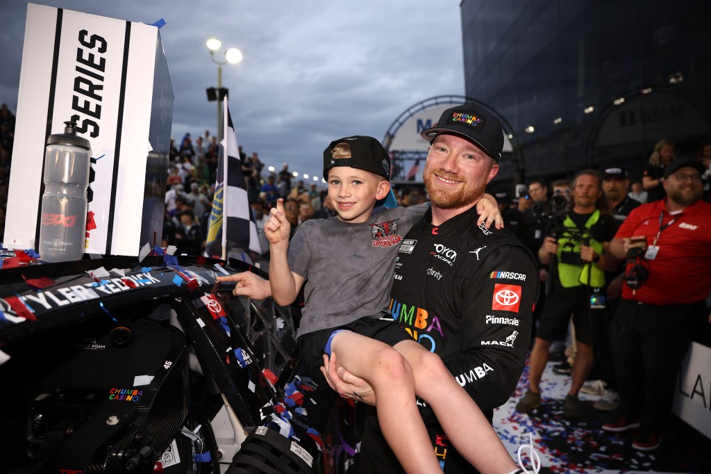 Tyler Reddick, driver of the #45 Chumba Casino Toyota, and son, Beau Reddick pose with the winner sticker on his car in victory lane after winning the NASCAR Cup Series Daytona 500 at Daytona International Speedway on February 15, 2026. 