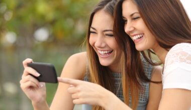 Two people laughing while watching a video on a smartphone.