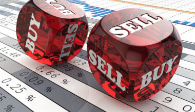 Dice with the words Buy and Sell printed on them laying on a printout of financial data.