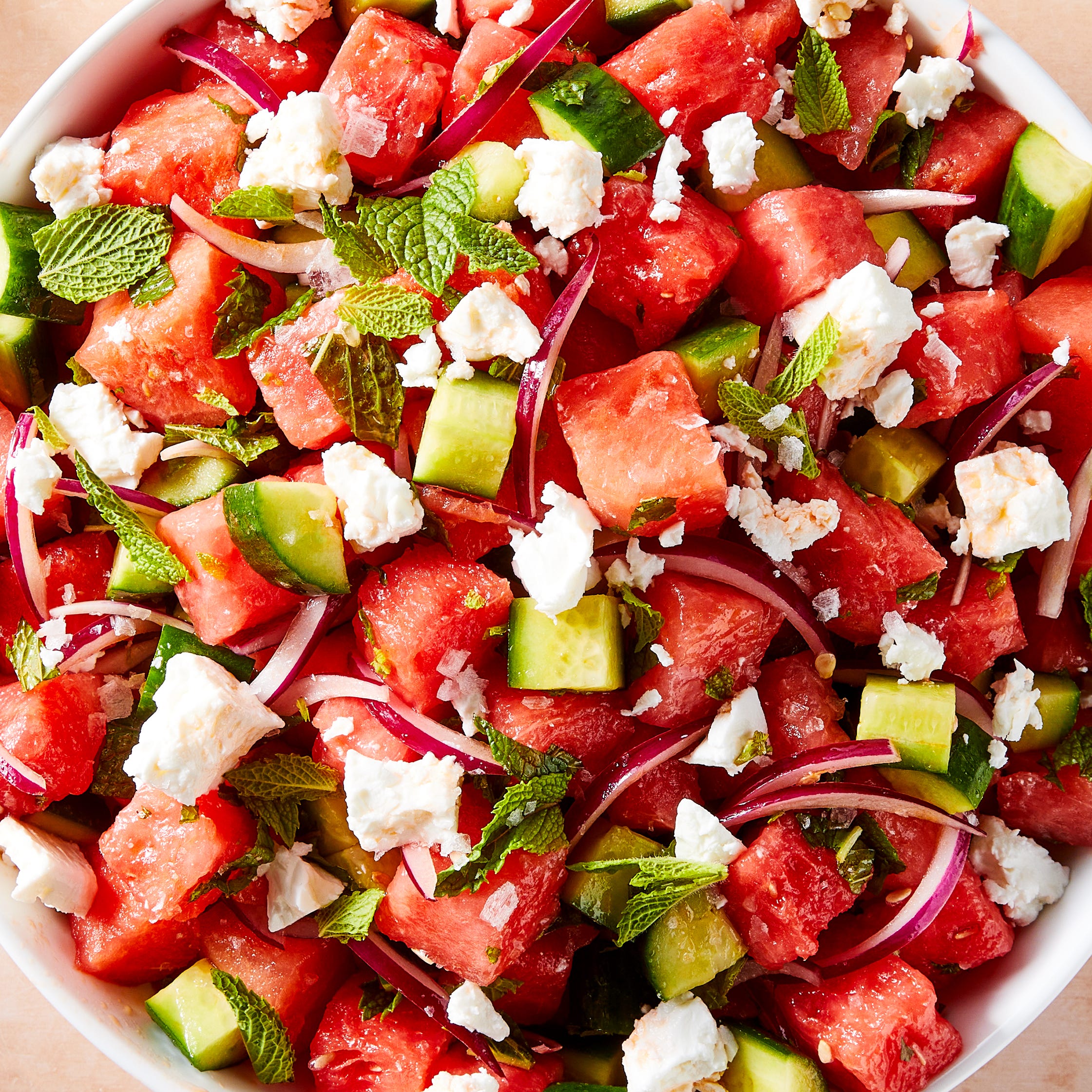 watermelon cubes, feta, red onion, and mint in a bowl