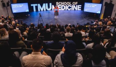 A woman standing at a podium at the centre of an auditorium.