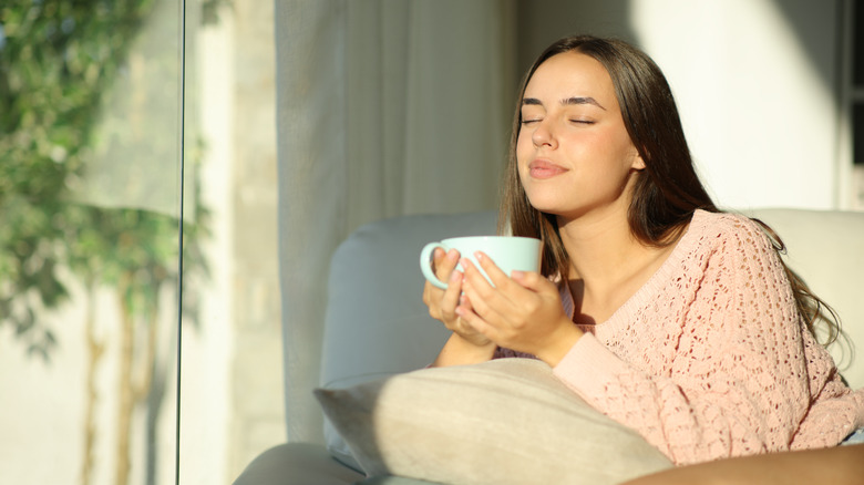 A woman relaxes in the sunshine with a mug