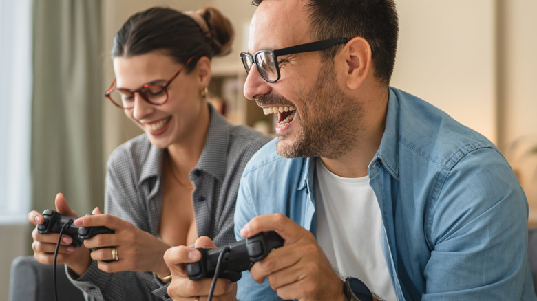 A man and a woman holding game controllers and smiling