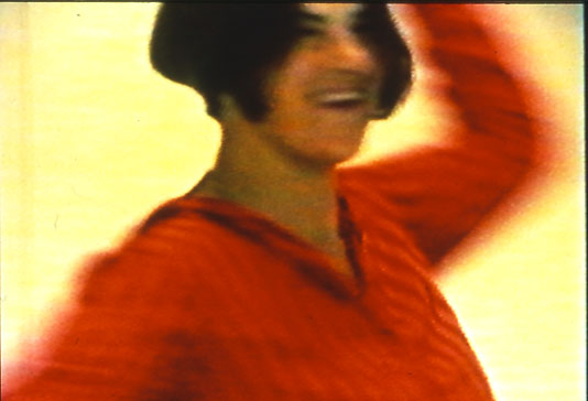 Tracey Emin dancing in red, with dark hair.