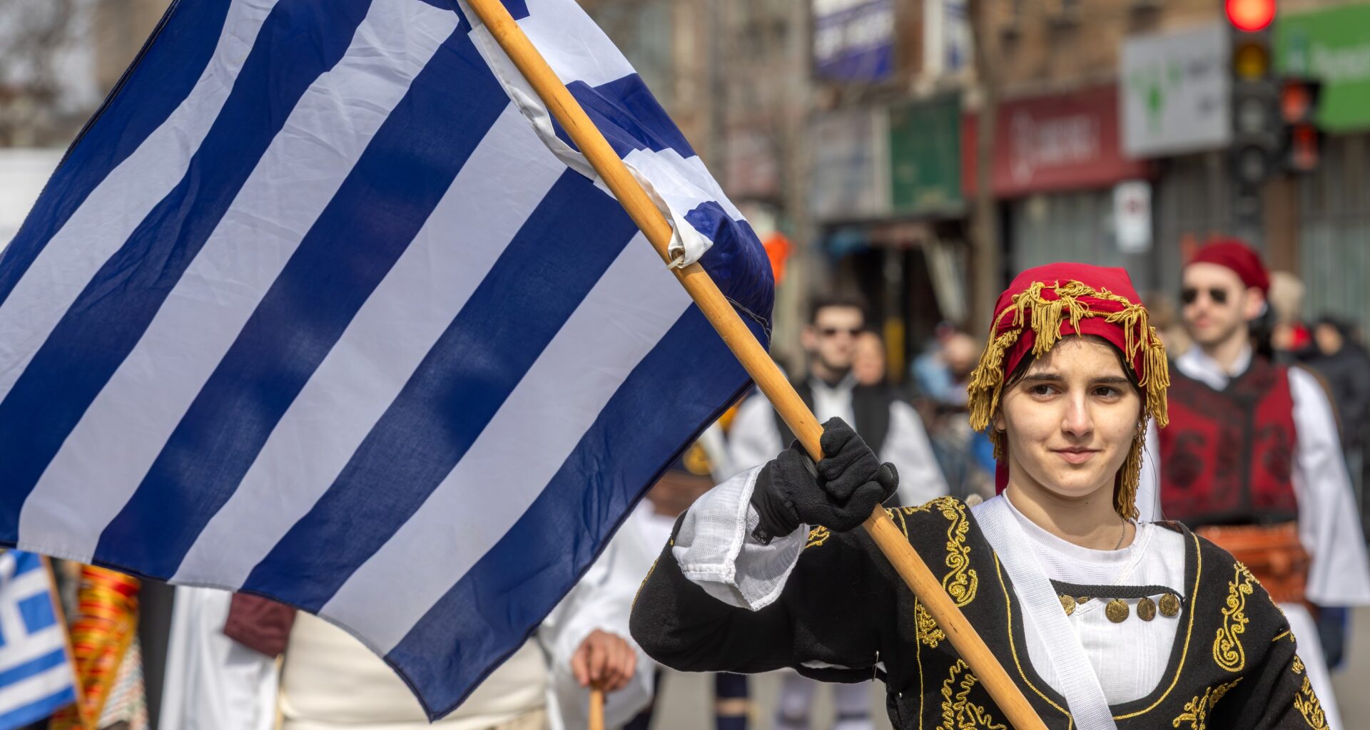A parade participant waves the Greek flag.