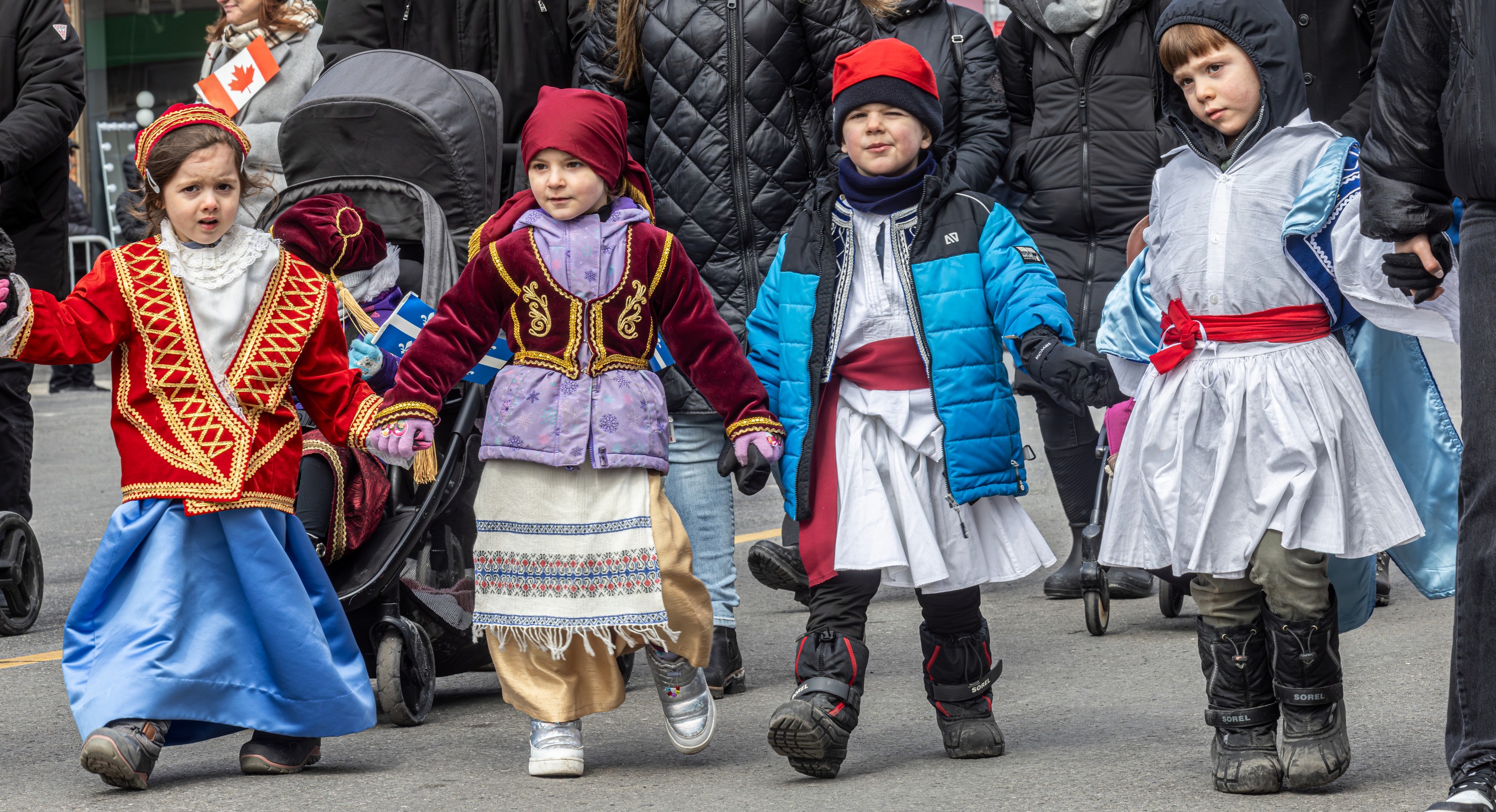 Four children walk hand in hand in a Greek Independence Day parade.